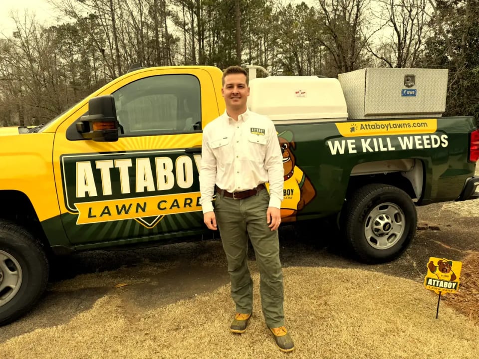 Tyler from Attaboy Lawn Care with branded service truck